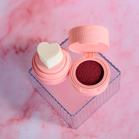 Makeup compact with heart-shaped sponge on a pink background
