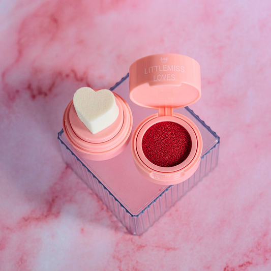 Makeup product with heart-shaped container and red powder on a pink marble background