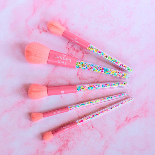 Set of pink makeup brushes with colorful handles on a pink marble background