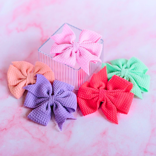 Set of colorful textured hair bows on a pink marble background