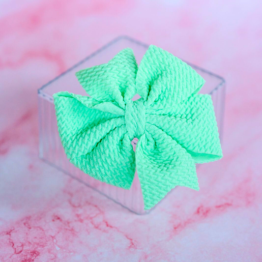 Green hair bow on a pink and white marble background