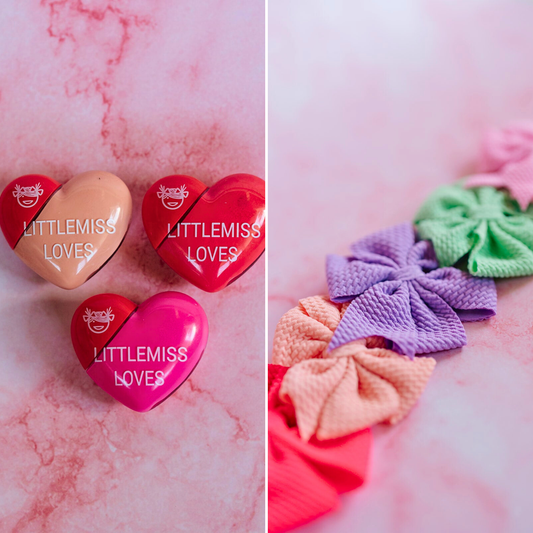 Heart-shaped containers with 'LITTLEMISS LOVES' branding on a pink marble background, accompanied by colorful hair ties.