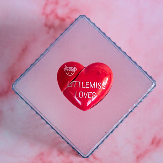 Red heart-shaped container with 'LITTLEMISS LOVES' text on a pink marble background