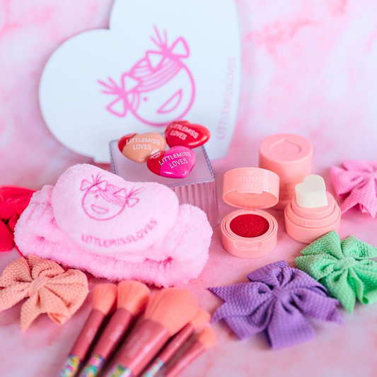 Makeup set with heart-shaped containers, brushes, and decorative bows on a pink background.