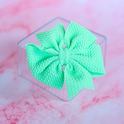 Green hair bow on a pink and white marble background