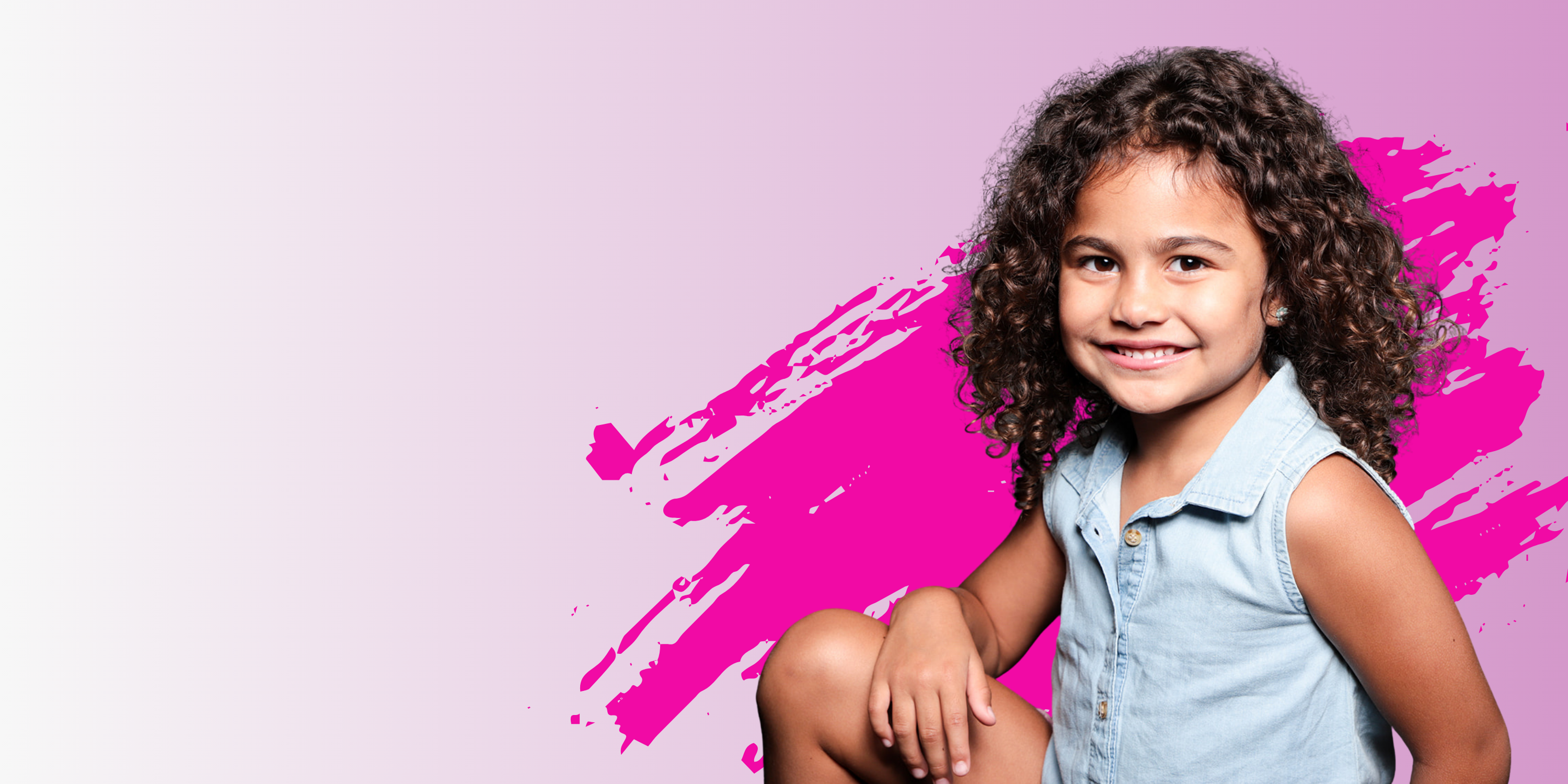Young girl with curly hair sitting against a pink and purple background