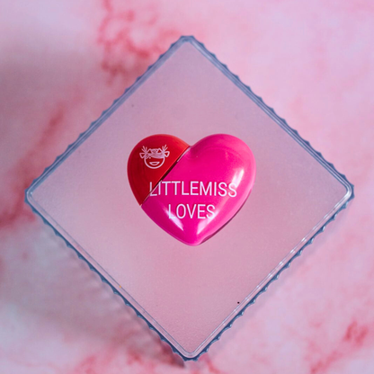 Heart-shaped product with 'LITTLEMISS LOVES' branding on a pink marble background